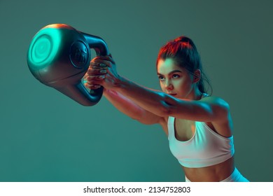 Portrait sportive woman workout  doing exercises and sports equipment isolated green studio background in neon light  Sport  gym  action  motion  beauty concept  Fitness  hobby  health