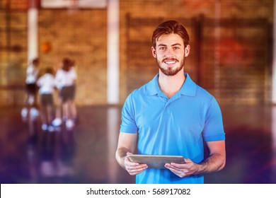 Portrait of sports teacher using digital tablet in basketball court at school gym - Powered by Shutterstock