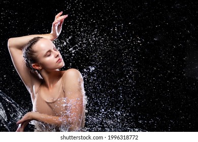 Portrait of sports woman doing stretching under drops of rain. Girl dancer is dancing. Drops of water fall on face against black background. Freedom, freshness concept. Modern art and beauty.