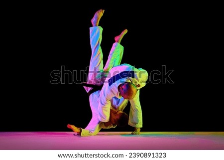 Portrait of sportsmen, martial arts fighters in white kimono fighting performing techniques in motions isolated black background. Concept of martial art, combat sport, health, energy, fit. Copy space