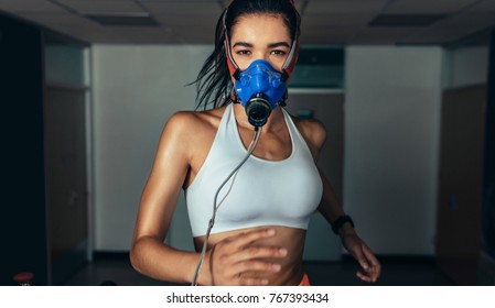 Portrait Of Sportswoman With Mask Running On Treadmill In Gym. Female Athlete In Sports Science Lab Measuring Her Performance.