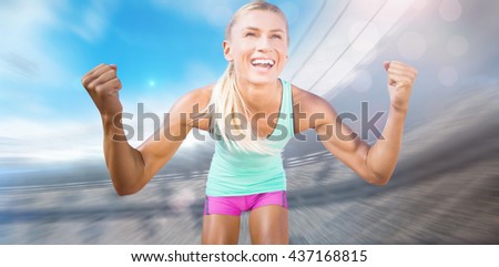 Portrait of sportswoman smiling and raising arms against view of a stadium