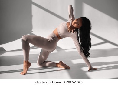 Portrait of sporty athletic woman in white sportswear doing stretching, enjoying sport exercises, stretching legs, practicing yoga. Shot indoors with big window - Powered by Shutterstock