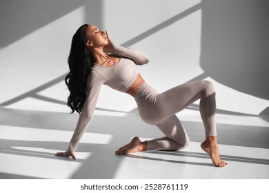 Portrait of sporty athletic woman in white sportswear doing stretching, enjoying sport exercises, stretching legs, practicing yoga. Shot indoors with big window - Powered by Shutterstock