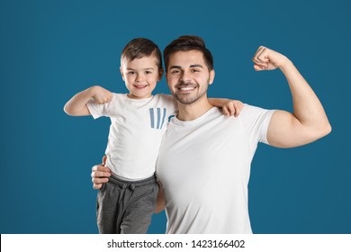 Portrait Of Sporty Dad And His Son On Color Background