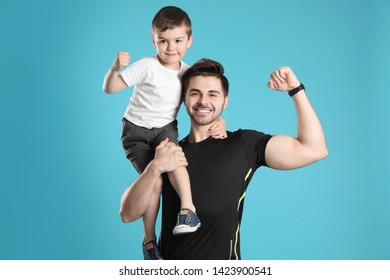 Portrait Of Sporty Dad And His Son On Color Background