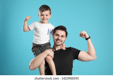 Portrait Of Sporty Dad And His Son On Color Background