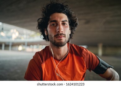 Portrait of a Sporty fit serious athletic young man with earphone in his ears looking at camera - Shutterstock ID 1624101223