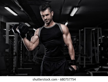 Portrait Of Sporty Healthy Strong Muscle Charismatic Happy Smiling Handsome Man Bodybuilder Hard Training Workout In Well-equipped Gym Doing Biceps Exercises With Dumbbells In Black T-shirt Outfit