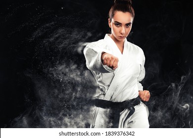 Portrait of sporty karate and taekwondo woman in white kimono with black belt on dark background. - Powered by Shutterstock