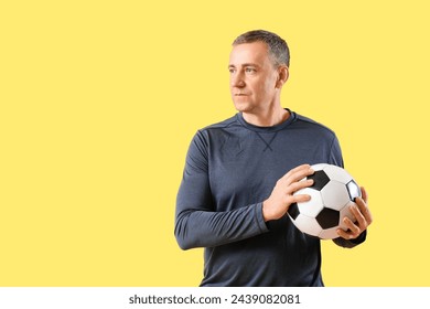 Portrait of sporty middle-aged man with soccer ball on yellow background - Powered by Shutterstock