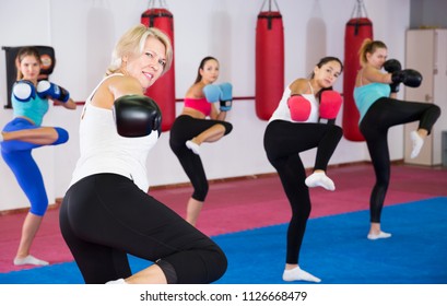 Portrait Of Sporty Senior Woman Who Is Boxing In Group In Gym.