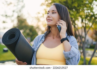 Portrait Of A Sporty Woman Taking Break From Workout, Walking The Park And Using A Mobile Phone To Talk To Someone. Sport, Hobby, Technology Concept