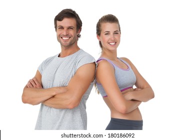 Portrait of a sporty young couple with arms crossed over white background