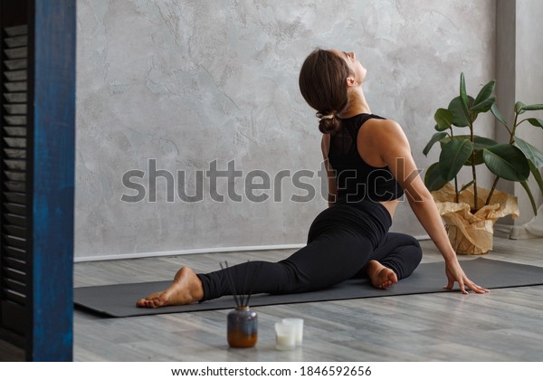 Portrait of sporty young woman doing exercises on\
yoga lesson at home. Beautiful girl practicing pigeon yoga pose.\
Yoga postures,meditation,relaxation,stress management,wellbeing and\
health.