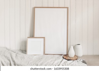 Portrait and square empty wooden frame mockups with linen cloth and modern ceramic vases. White beadboard wainscot wall paneling background. Scandinavian interior, home design. Art concept.