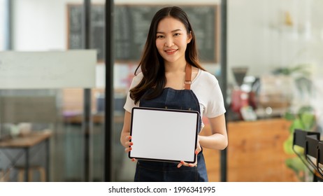 Portrait of Starting small Asian young businesses owners showing tablet with blank screen at coffee shop. - Powered by Shutterstock