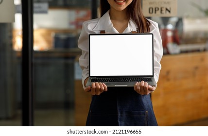 Portrait Of Startup Successful Small Business Owner Wearing An Apron And Showing Laptop Computer Screen Isolated On A Black Background, 