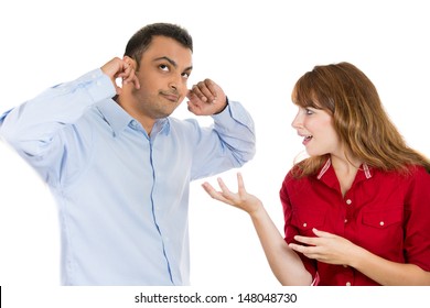 A portrait of a stressed couple going through hard times in their relationship, isolated on a white background . Young woman trying to explain something to a man, he is annoyed and closes his ears.