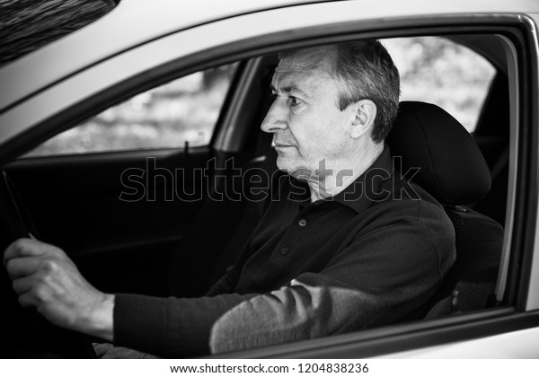 Portrait of stressed mature\
man in car drivers seat. Crisis of middle age and man\'s life after\
50 years. Senior serious or sad or depressed man sitting in his\
car, toned