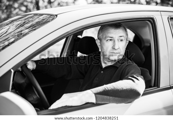 Portrait of stressed mature\
man in car drivers seat. Crisis of middle age and man\'s life after\
50 years. Senior serious or sad or depressed man sitting in his\
car, toned