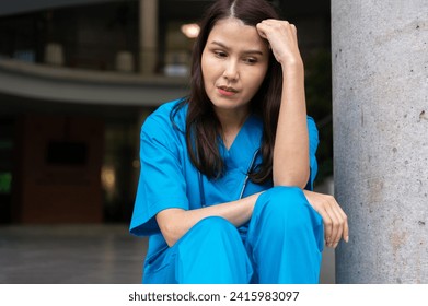 Portrait of stressed and overworked female doctor medical worker surgeon sitting on the floor near the operating room in the hospital and take off the mask - Powered by Shutterstock