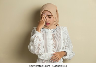 portrait of stressed sick muslim woman with headache; ill woman suffers from vertigo, dizziness, migraine, hangover, health care concept; young adult asian woman model
