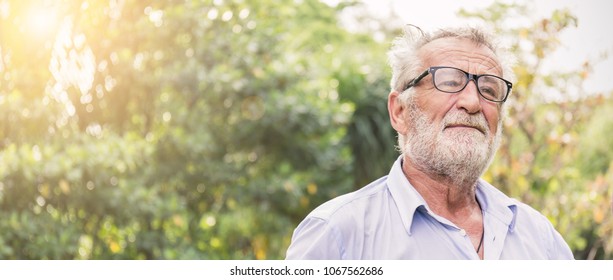 Portrait of stressful sad senior elderly caucasian old man in the park outdoors with copy space. Spring healthcare lifestyle eldery stress painful retirement golden age crisis concept panoramic banner