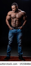 Portrait of a strong afro-american man showing off his physique against black background.
