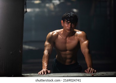 Portrait of Strong Asian sportsman athlete in sportswear do sport training workout bodybuilding exercise in abandoned building. Shirtless man bodybuilder practicing muscular build in dark place gym - Powered by Shutterstock