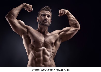 portrait of strong Athletic Fitness man showing big muscles over black background