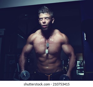 Portrait of a strong guy doing exercises with dumbbells