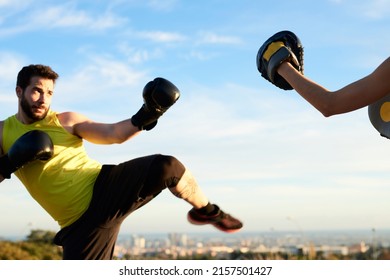 Portrait Of Strong Man In Boxing Gloves Training In Park Against Sky. Copyspace.