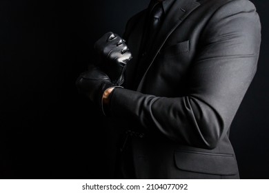 Portrait of Strong Man in Dark Suit Pulling on Black Leather Gloves. Concept of Mafia Hitman or Gentleman Assassin