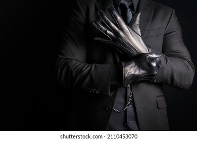 Retrato de hombre fuerte en traje oscuro sobre guantes de cuero negro. Actividad criminal oscura. Amenaza de violencia peligrosa