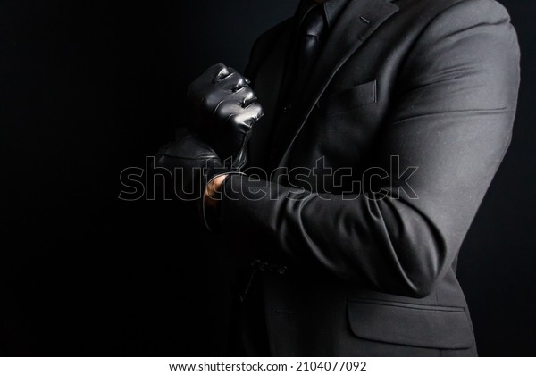 Portrait of Strong\
Man in Dark Suit Pulling on Black Leather Gloves. Concept of Mafia\
Hitman or Gentleman\
Assassin