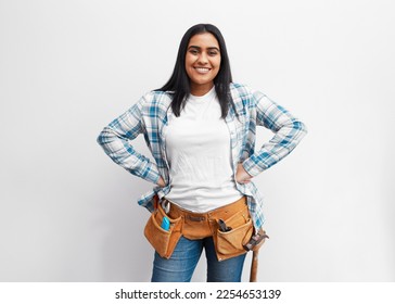 Portrait of a strong young Indian woman about to do DIY at home with tool belt - Powered by Shutterstock