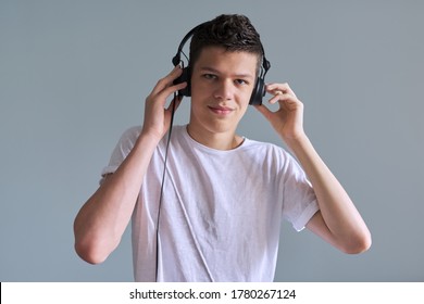 Portrait Of Student Boy Teenager In Headphones Listening Audio Lessons, Online Training. Gray Inside Background