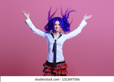 Portrait of a student girl with purple hair in white blouse and checkered skirt posing on pink background at studio. Japanese style anime. 