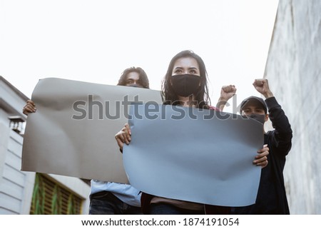 Portrait students holding blank paper conducting demonstrations by following health protocols