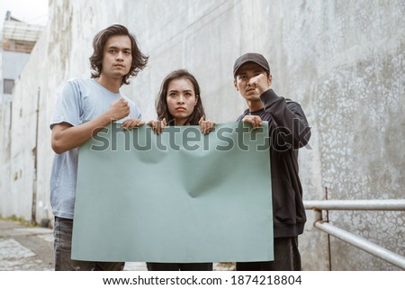 Portrait students holding blank paper who are burning with enthusiasm doing a demonstration together