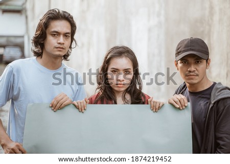 Portrait students holding blank paper who are burning with enthusiasm doing a demonstration together