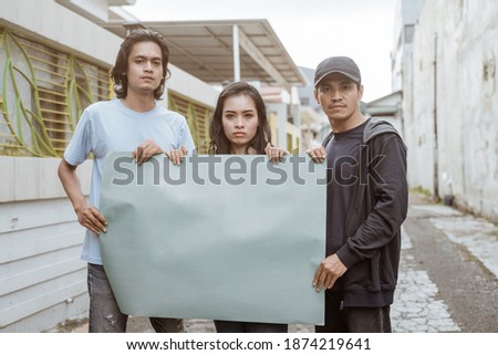 Portrait students holding blank paper who are burning with enthusiasm doing a demonstration together