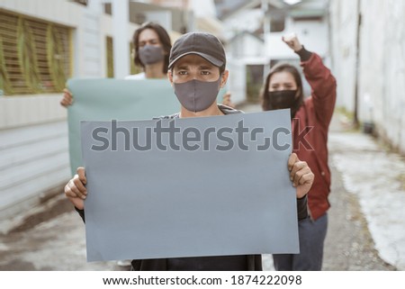 Portrait students holding blank paper conducting demonstrations by following health protocols