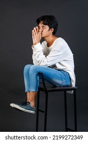 Portrait Studio Full Body Shot Of Asian Young LGBTQ Gay Glamour Handsome Male Model In Casual White Shirt Jeans Sneakers Sitting On Tall Chair On Black Background.