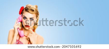 Portrait studio image - pensive, puzzled or thinking woman with phone tube. Unhappy pin up girl. Retro and vintage concept. Light blue color background with copy space area. Wide banner composition.