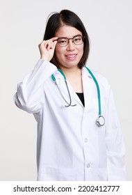 Portrait Studio Isolated Cutout Closeup Shot Of Asian Professional Successful Female Doctor In Lab Coat With Stethoscope Smiling Look At Camera Holding Hand Adjusting Eyeglasses On White Background.