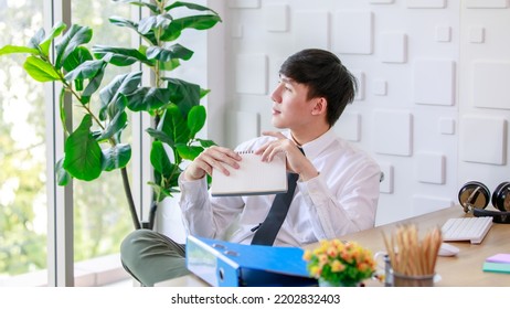 Portrait Studio Shot Of Asian Professional Successful Male Businessman Employee In Formal Shirt With Necktie Sitting Look At Camera At Working Desk With Computer Monitor Keyboard Mouse And Stationery.