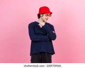 Portrait studio shot Asian young urban teen fashion male model in street style outfit long sleeve shirt red bucket hat funny glasses standing crossed arms smiling look at camera on pink background. - Powered by Shutterstock