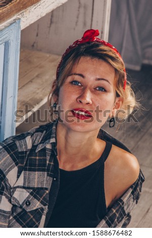 Portrait of a stunning smiling girl with red lips, dressed in a checkered red shirt and a bandana on her head. Model posing in retro fashion style and vintage concept